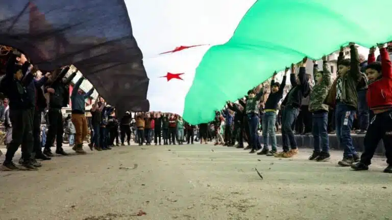 أطفال سوريون في إدلب وعلم الثورة في مظاهرة ضد تقارب تركي مع النظام (6/1/2023/فرانس برس)